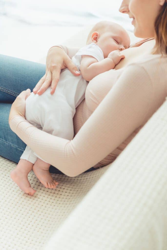 cropped view of mother breastfeeding her child in apartment